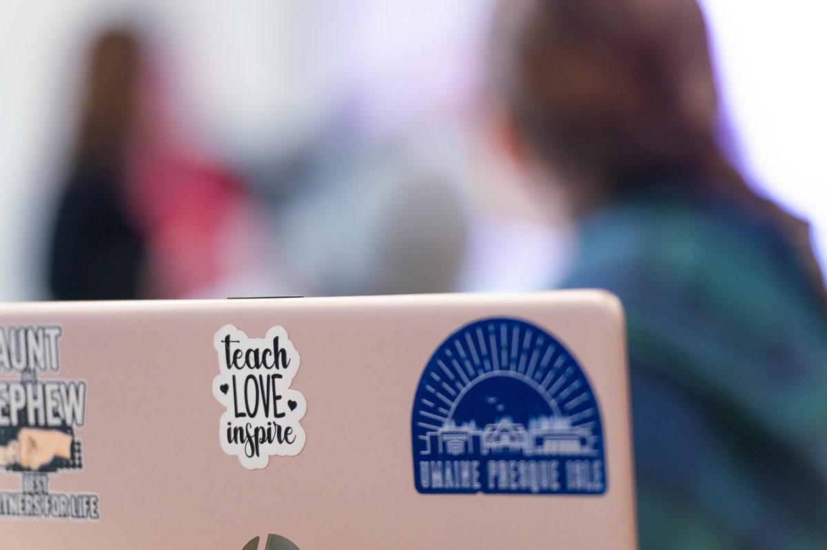 Open laptop with "Teach, Love, Inspire" and UMPI decals