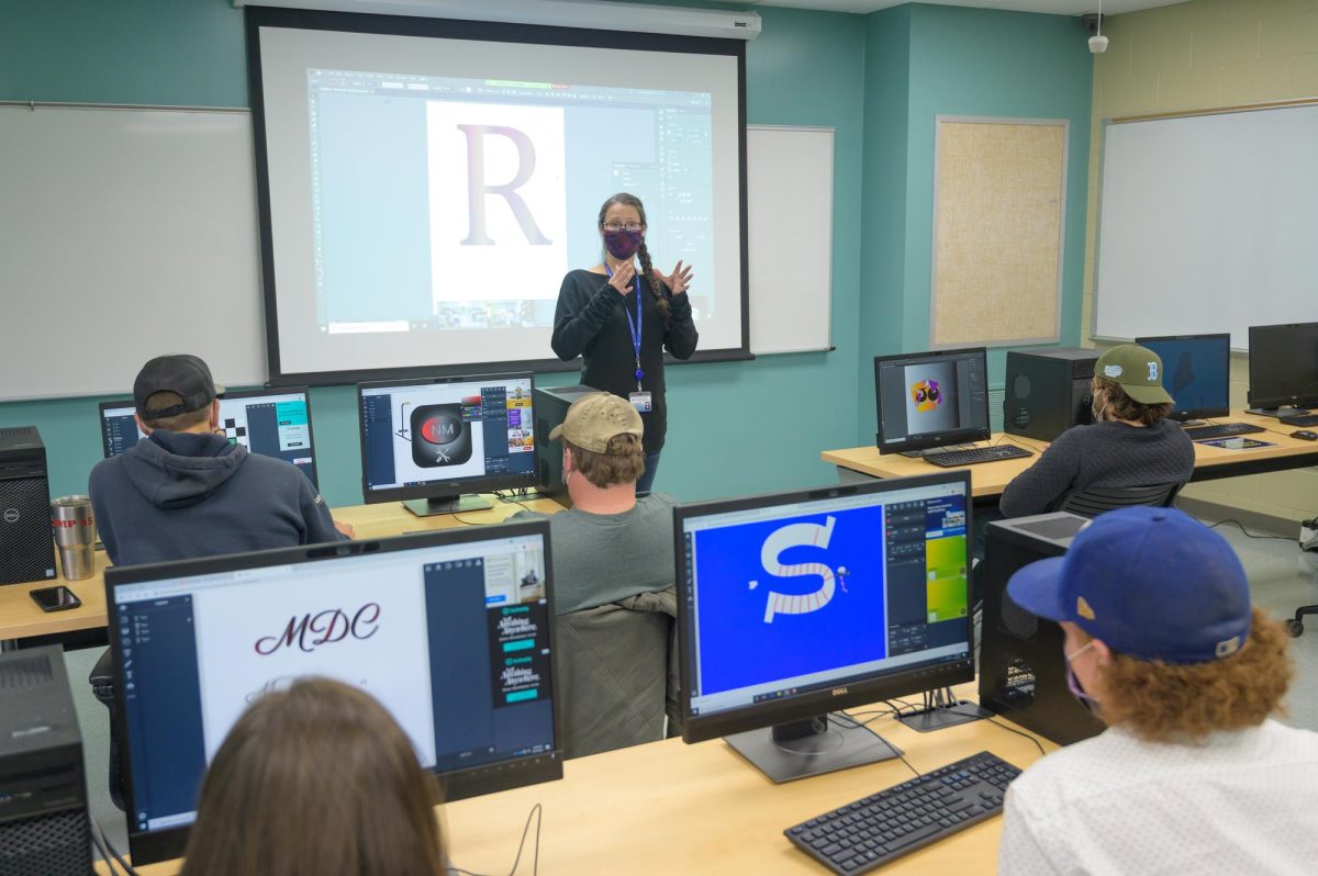 Professor teaching a class in a computer lab using a projector as an aid